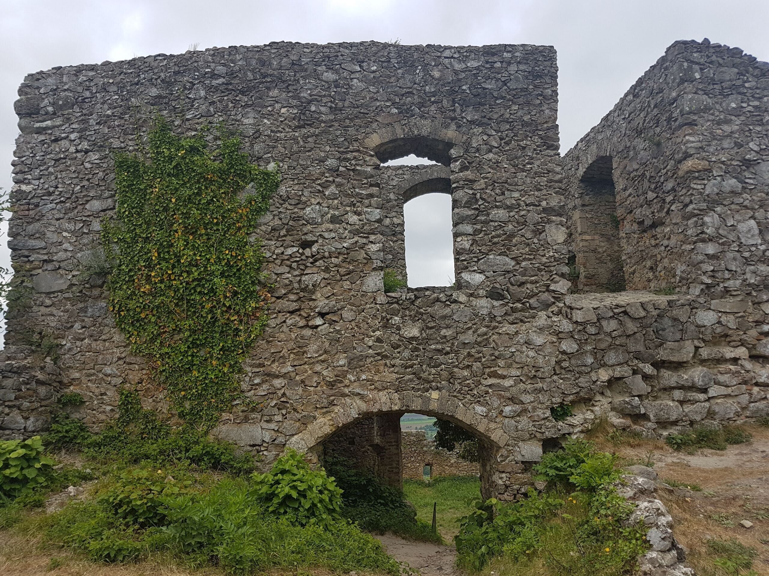 Rovine in pietra con archi e vegetazione rigogliosa.