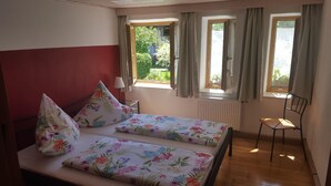 Ein Schlafzimmer mit einem Bett, zwei Kissen, einem Stuhl, einem Fenster und einer Heizung.