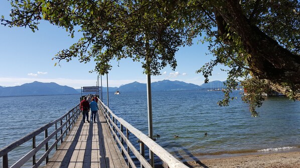 Een houten steiger die zich uitstrekt over een meer, met bergen op de achtergrond.