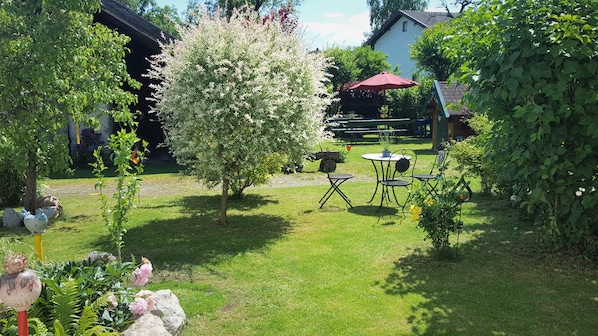 A garden with a small lawn, a picnic table, and a red umbrella.