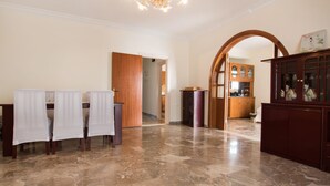 A spacious room with a marble floor, a chandelier, a wooden cabinet with glass doors, and a dining area with chairs and a table. - Mountain view villa !!! (Karpathos)