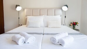 A double bed with white linens and pillows, two bedside lamps, and a vase with flowers on a nightstand. - Mountain view villa !!! (Karpathos)