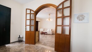 A hallway with a wooden door, a white sofa, and a chandelier. - Mountain view villa !!! (Karpathos)