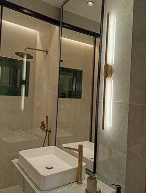 A modern bathroom with a large mirror, a shower, and a sink.