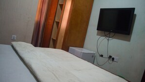A room with a bed, a television mounted on the wall, and a power outlet. - Owee's Place (Lagos)