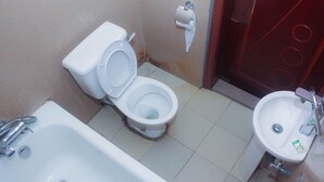 A bathroom with a toilet, sink, and bathtub. - Owee's Place (Lagos)