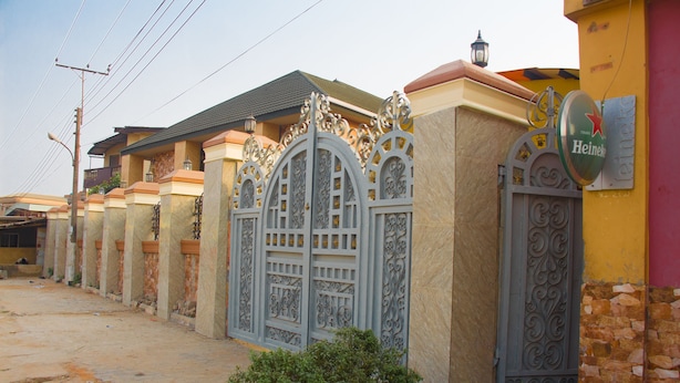 A row of houses with ornate metal gates and a Heineken sign on the right. - Owee's Place (Lagos)