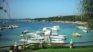 A marina with various boats docked, surrounded by greenery and a clear sky.