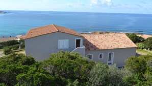 A two-story building with a tiled roof, a balcony, and a view of the sea.