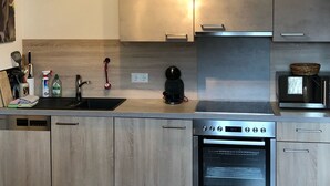 Een moderne keuken met lichte houten keukenkastjes, een roestvrijstalen oven en een opgehangen hertenkop.