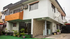 Ein zweigeschossiges Haus mit Balkon, Satellitenschüssel und Blumentöpfen.