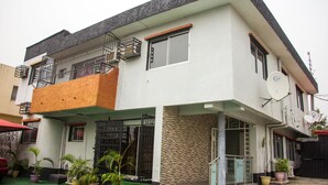Ein zweistöckiges Gebäude mit Balkon, Satellitenschüssel und Blumentöpfen.