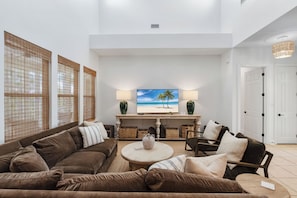 A modern living room with a brown sofa, a round coffee table, and a television displaying a beach scene.