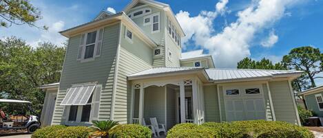 A two-story house with a porch, a garage, and a golf cart parked outside.