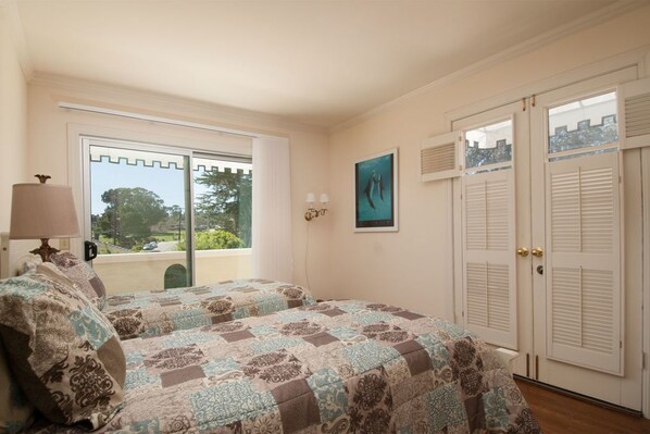 Une chambre avec deux lits, une fenêtre donnant sur un beau paysage, un tableau accroché au mur et une porte avec des volets à persiennes.