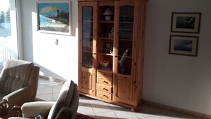 A living room with a wooden cabinet, a sofa, and a painting on the wall. - Baltic Sea holiday with sea view in a prime location in Göhren on Rügen (Göhren)