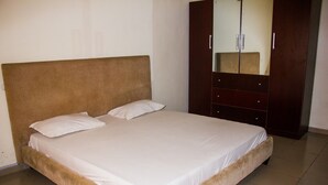 A bedroom with a large bed, a wardrobe, and a mirror. - David Royal Suites (Lagos)