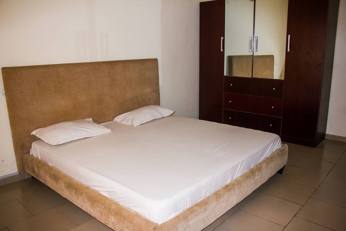A bedroom with a large bed, a wardrobe, and a mirror.