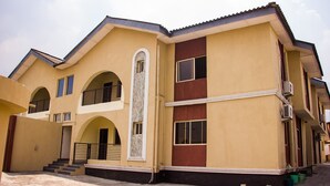 A multi-story building with a yellow facade, multiple windows, and a central staircase. - David Royal Suites (Lagos)