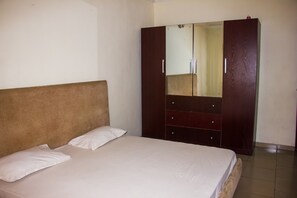 A bedroom with a bed, a wardrobe, and a mirror. - David Royal Suites (Lagos)