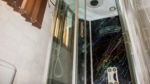 A shower with a glass door, a showerhead, and a visible drain. - David Royal Suites (Lagos)
