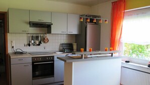 A modern kitchen with a central island, built-in oven, and stainless steel appliances. - Apartment right on the forest in a quiet, secluded location in the heart of the Vulkaneifel (Gerolstein)