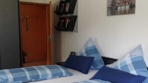 A room with two beds, a bookshelf, and a door. - Apartment right on the forest in a quiet, secluded location in the heart of the Vulkaneifel (Gerolstein)