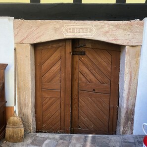 Une porte à double battant en bois, ornée d’un motif en chevrons, avec un loquet métallique et une inscription au-dessus indiquant « H 1821 ».