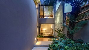 A modern building with a glass entrance, a staircase, and lush greenery.