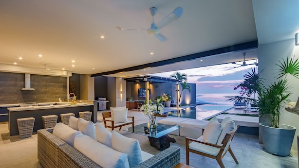 A modern living room with a sofa, chairs, a coffee table, and a view of the ocean.