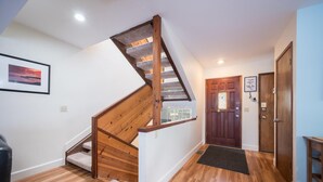 A wooden staircase with a landing, a framed picture on the wall, and a door with a welcome sign.