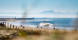 Een strand met een vuurtoren en een steiger op de achtergrond.
