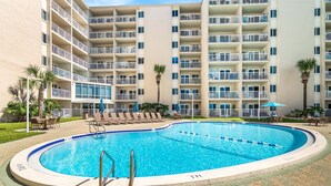 A hotel with a swimming pool surrounded by lounge chairs and umbrellas. - 214- Escape and Relax at this beach front paradise (Destin)