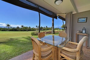 Relax in a shaded outdoor seating area surrounded by lush greenery and palm trees.