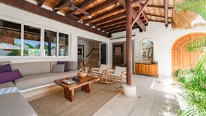Un amplio salón con techo de madera, un sofá, una mesa de centro y una mesa de comedor.