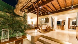 Un amplio salón con techo de madera, un comedor con una gran mesa de madera, y una escalera que lleva a un nivel superior.