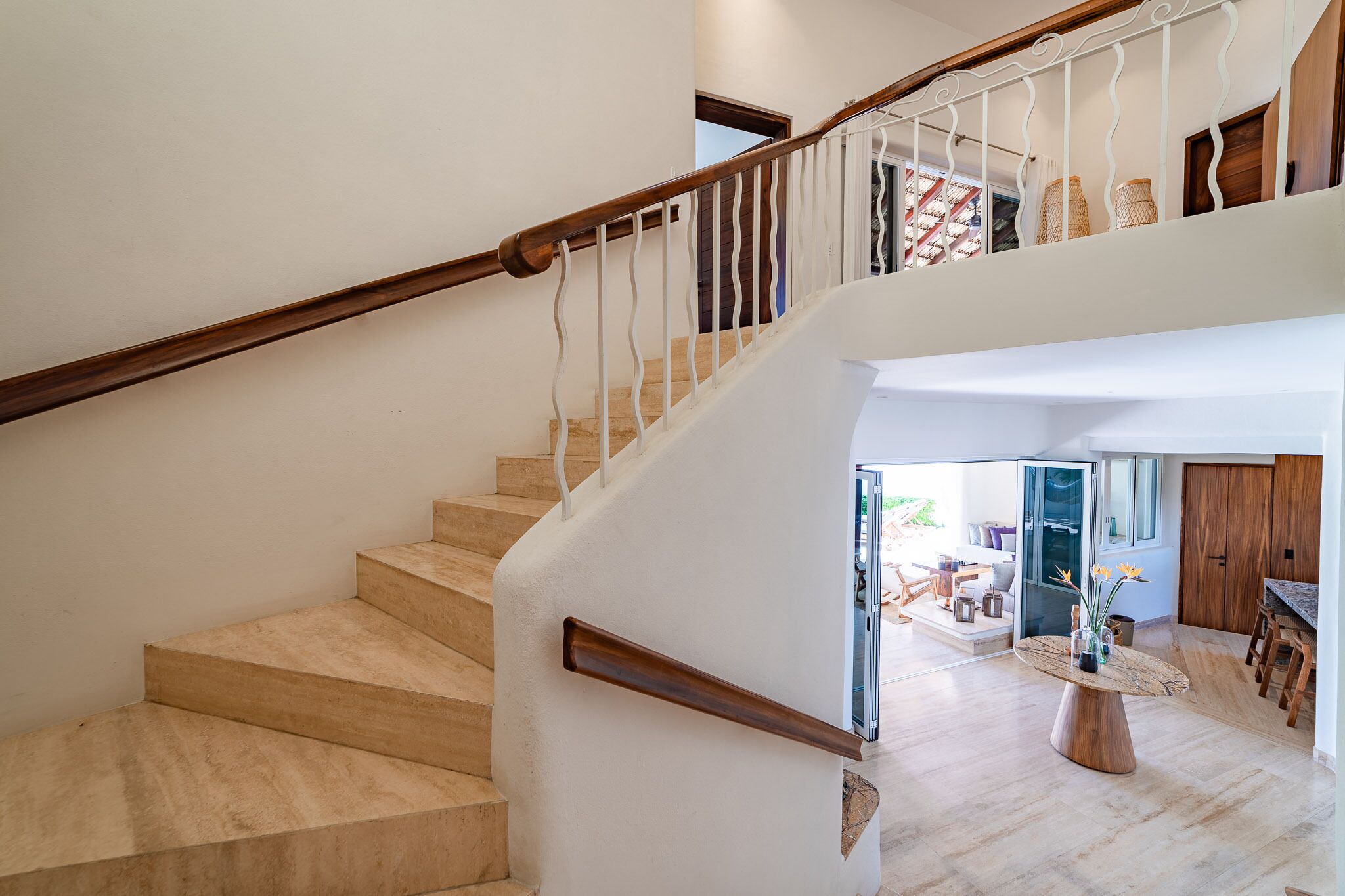 Una scala con ringhiere in legno e gradini color beige che conduce a un piano superiore.