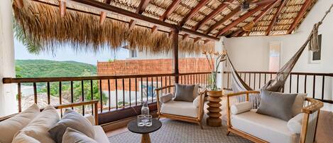 Una habitación con techo de paja, una hamaca, un sofá y vistas al verdor.