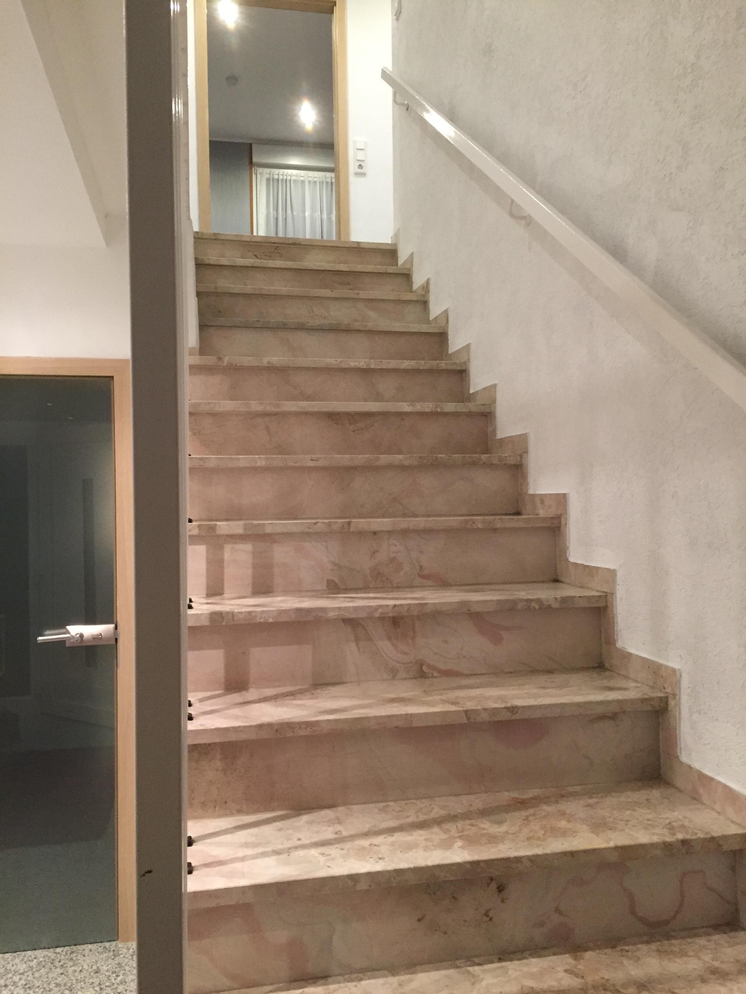 Eine Treppe mit Handlauf, die zu einem Zimmer mit Fenster und Tür führt.