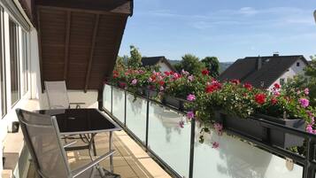 Ein Balkon mit Glastrennwand, einem Tisch und zwei Stühlen.