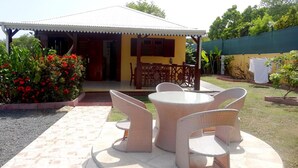 A covered outdoor seating area with wicker furniture, a small table, and chairs.