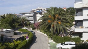 Una calle residencial con edificios modernos, una palmera y coches aparcados.