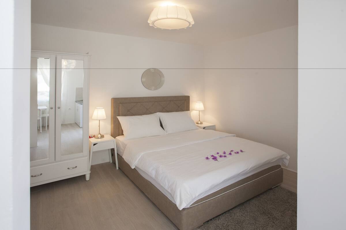 Un dormitorio con cama, mesitas de noche, un espejo y un armario.
