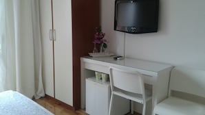 Un dormitorio con cama, un escritorio con silla, un televisor y un armario.