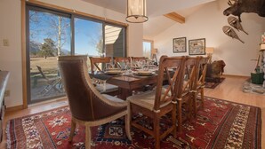 Un comedor con una mesa grande dispuesta para seis personas, sillas de madera y un tapete rojo estampado.