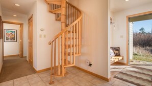 Una escalera de madera en un pasillo, con una puerta que da a otra habitación.