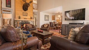 Una sala de estar acogedora con muebles de cuero, una chimenea de piedra y una cabeza de venado decorativa.