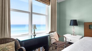 Una habitación con un ventanal grande, un escritorio, una silla, una cama y una lámpara.