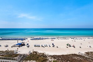 Una platja amb files de papereres blaves, sorra daurada i un cel blau i clar.