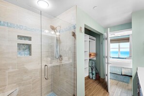 A bathroom with a glass shower enclosure, a tiled floor, and a view of the ocean through a window. - 0507 - Fresh and Fun Coastal Condo (Panama City Beach)